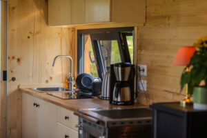 Küche mit Kaffeemaschine, Kühlschrank und Kamin